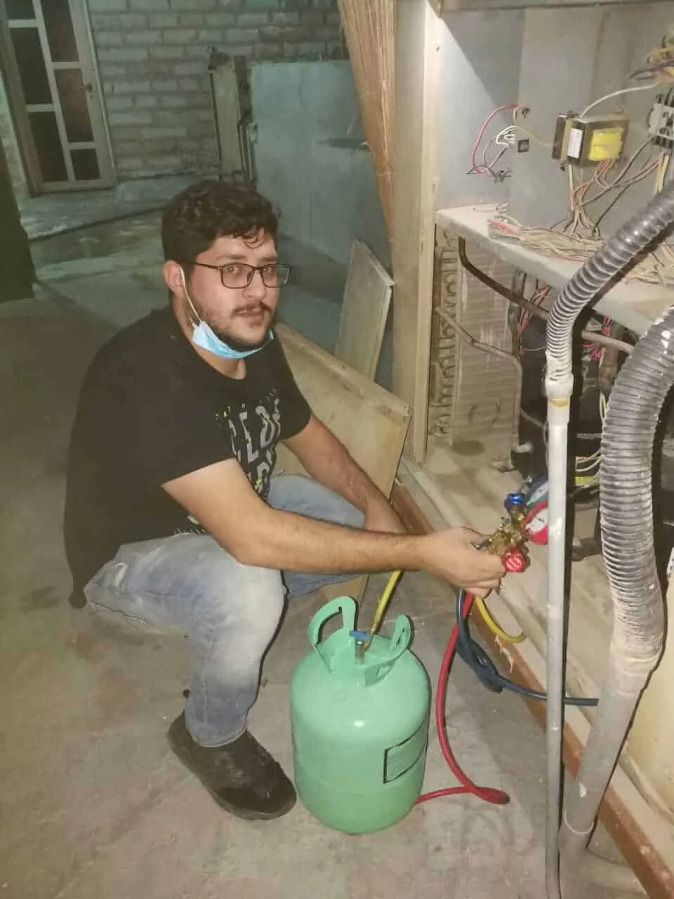 فني تكييف أثناء شحن غاز الفريون للمكيف