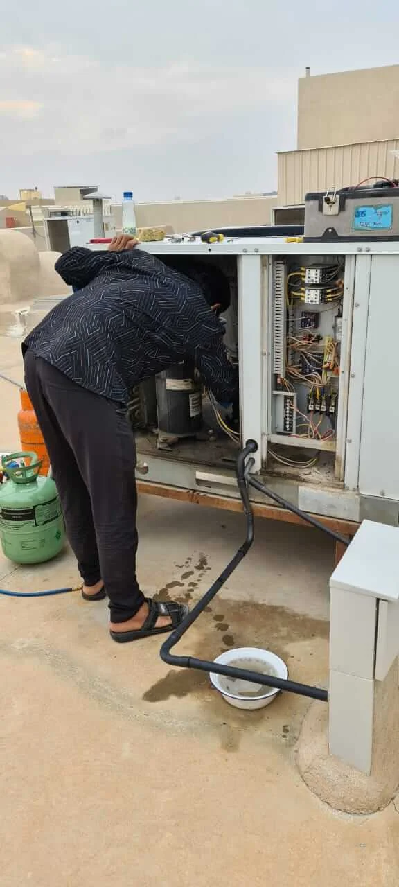 فني يفحص مكونات التحكم في نظام تكييف مركزي أثناء الصيانة