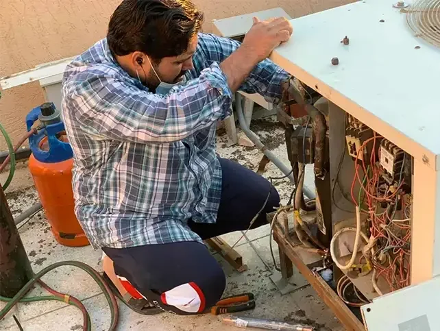 فني تكييف من AC Repair أثناء فحص وصيانة مكيف في الكويت
